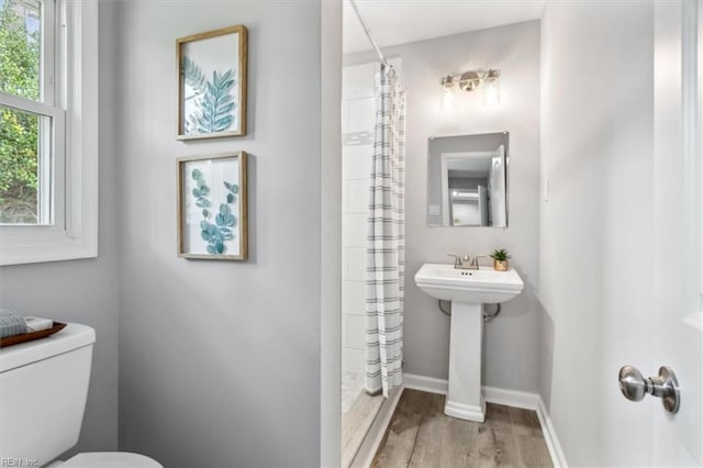 bathroom featuring toilet, curtained shower, baseboards, and wood finished floors
