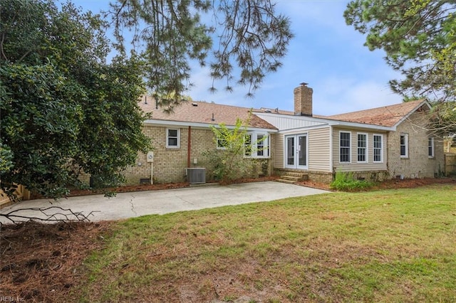 rear view of property with a patio, entry steps, brick siding, central AC, and a yard