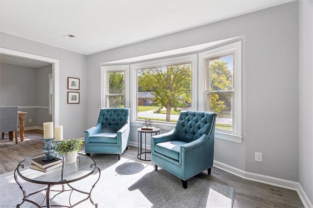 living area featuring baseboards, visible vents, and a healthy amount of sunlight