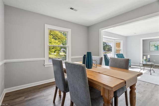dining space with baseboards, visible vents, and wood finished floors
