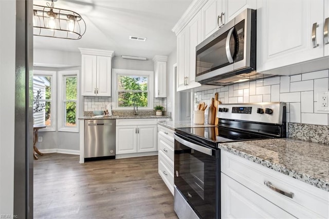 kitchen featuring a sink, light wood-type flooring, stainless steel appliances, visible vents, and white cabinets