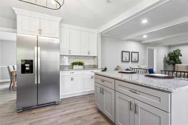 kitchen featuring stainless steel fridge, light wood finished floors, beam ceiling, white cabinetry, and backsplash