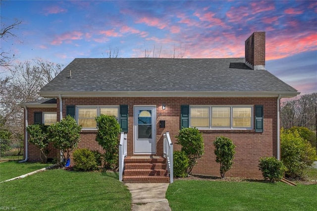bungalow-style house with a front lawn, a chimney, fence, and brick siding