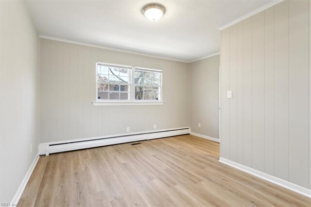 empty room with baseboards, wood finished floors, crown molding, and a baseboard radiator