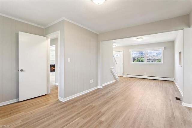 unfurnished room with baseboards, a fireplace, ornamental molding, a baseboard heating unit, and light wood-type flooring