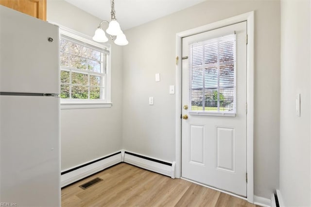 doorway featuring visible vents, a baseboard heating unit, light wood-style floors, and a notable chandelier