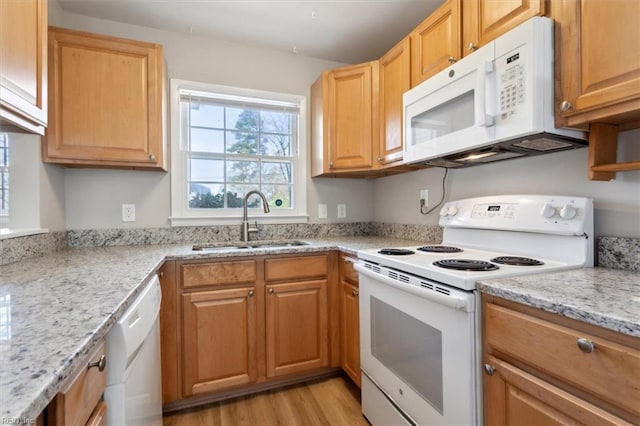 kitchen featuring light wood-style flooring, a sink, light stone counters, and white appliances