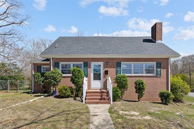 view of front of house with a front yard, a chimney, fence, brick siding, and entry steps