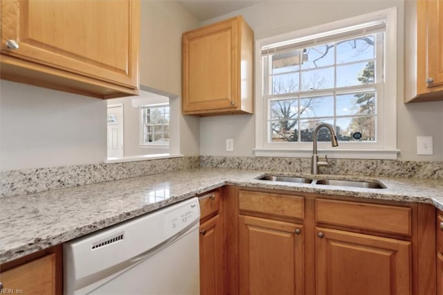 kitchen featuring light stone countertops, a sink, white dishwasher, and a healthy amount of sunlight