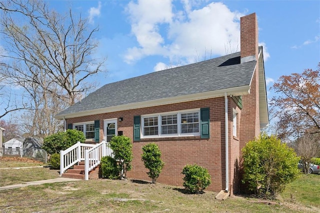 bungalow-style home featuring brick siding, a front lawn, and a chimney