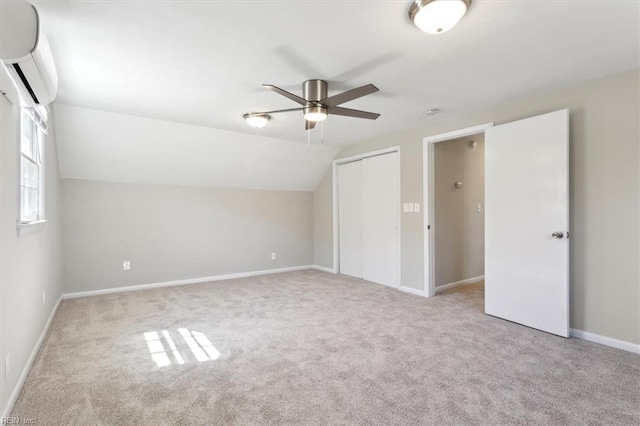 unfurnished bedroom featuring a closet, a wall mounted AC, carpet floors, and vaulted ceiling