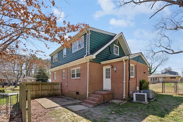 rear view of property with a gate, fence, central AC unit, crawl space, and brick siding