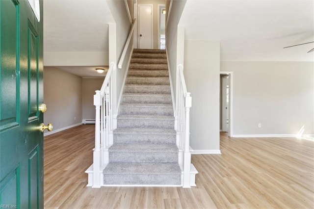 entryway with a baseboard radiator, light wood-style floors, baseboards, and stairway