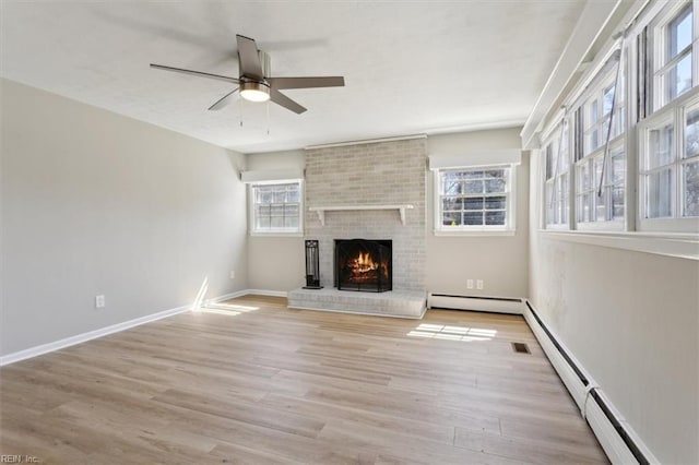 unfurnished living room with a baseboard heating unit, light wood-style floors, ceiling fan, a fireplace, and baseboard heating