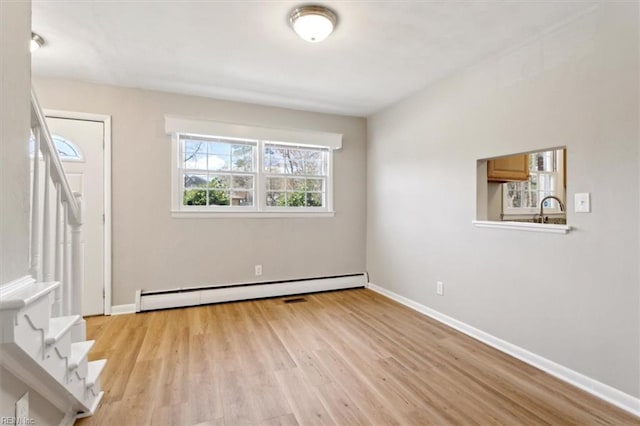 interior space featuring stairs, a sink, light wood finished floors, baseboards, and a baseboard heating unit