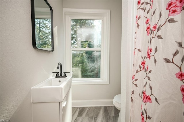 bathroom featuring a wealth of natural light, toilet, vanity, and baseboards