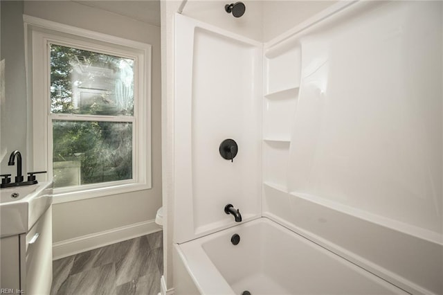 bathroom with baseboards, toilet, vanity, and washtub / shower combination