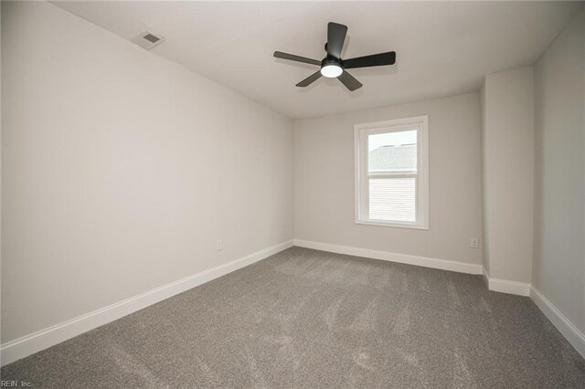 empty room with baseboards, visible vents, dark colored carpet, and ceiling fan