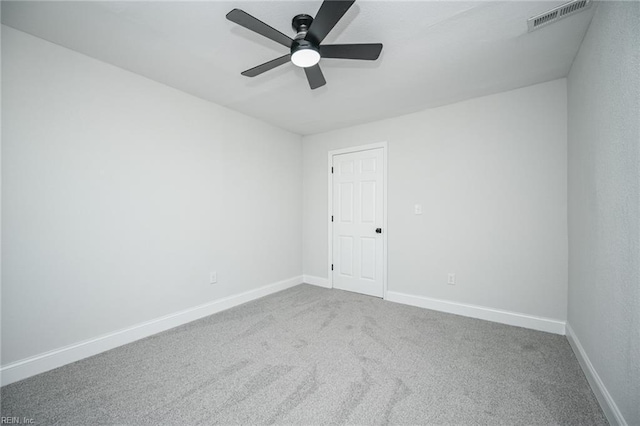 carpeted empty room with baseboards, ceiling fan, and visible vents