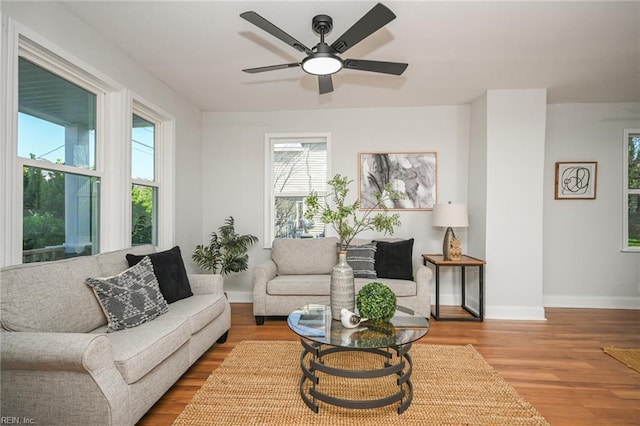 living room featuring baseboards, wood finished floors, and a ceiling fan