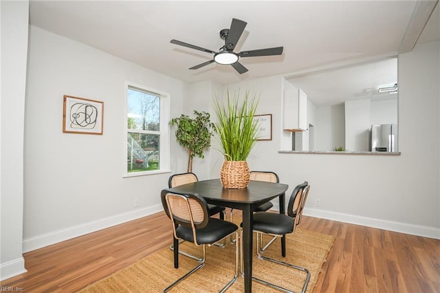 dining area featuring baseboards, ceiling fan, and wood finished floors