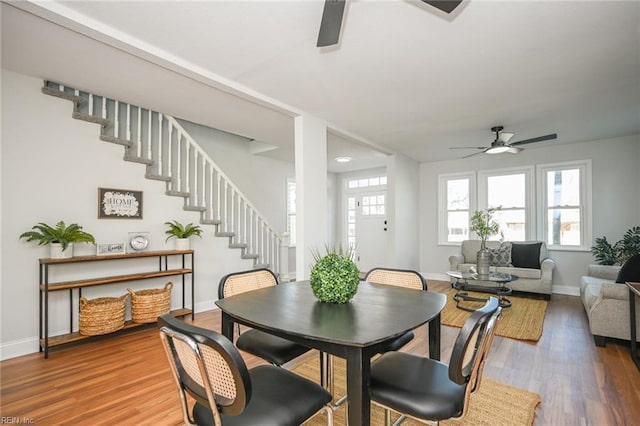 dining area with baseboards, wood finished floors, stairway, and a ceiling fan
