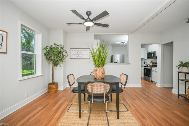 dining room featuring baseboards, a ceiling fan, and light wood-type flooring