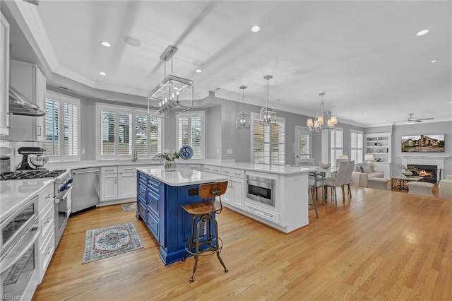 kitchen featuring a lit fireplace, light countertops, white cabinetry, appliances with stainless steel finishes, and blue cabinets