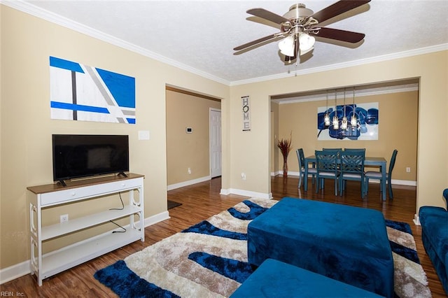 living area featuring ornamental molding, ceiling fan with notable chandelier, baseboards, and wood finished floors