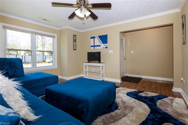 living room with visible vents, crown molding, baseboards, wood finished floors, and a ceiling fan