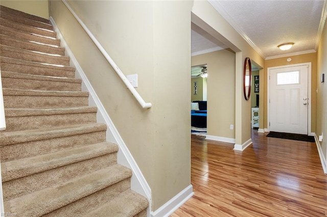 entrance foyer with a textured ceiling, wood finished floors, stairway, and ornamental molding