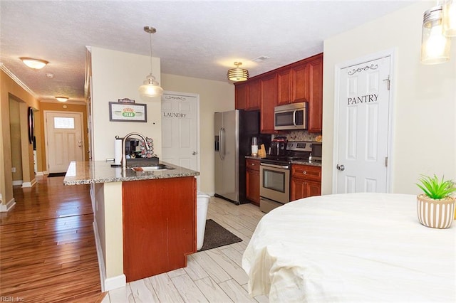 kitchen featuring a sink, appliances with stainless steel finishes, stone countertops, and a textured ceiling