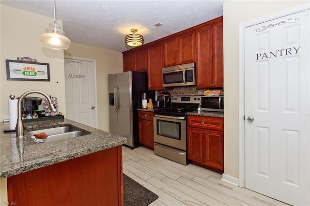 kitchen with light wood-type flooring, a textured ceiling, a sink, visible vents, and appliances with stainless steel finishes