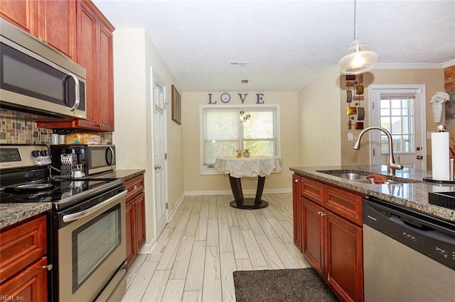 kitchen featuring tasteful backsplash, stainless steel appliances, a sink, reddish brown cabinets, and light wood-style floors