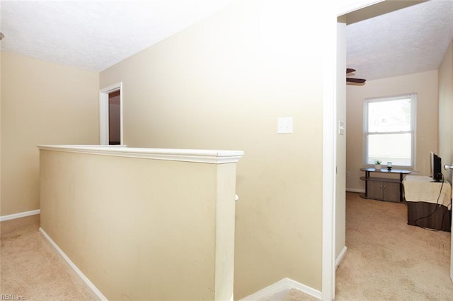 corridor with baseboards, an upstairs landing, carpet floors, and a textured ceiling