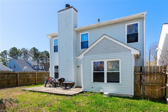 rear view of property featuring a lawn, a deck, fence, and a chimney
