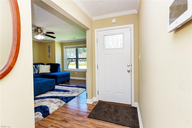 entrance foyer with a ceiling fan, crown molding, baseboards, and wood finished floors