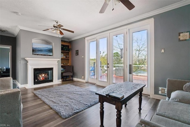 living room featuring baseboards, wood finished floors, a glass covered fireplace, and a ceiling fan