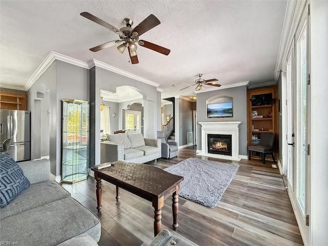 living area with wood finished floors, arched walkways, and a ceiling fan