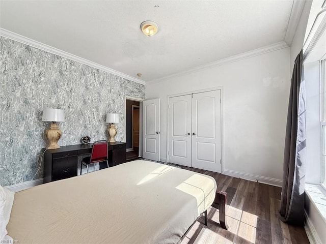 bedroom with ornamental molding, baseboards, wallpapered walls, a closet, and wood finished floors