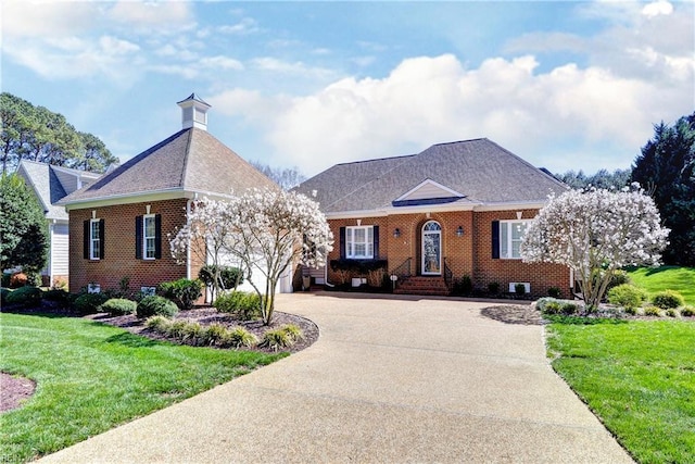 view of front of house featuring an attached garage, brick siding, a front lawn, and driveway