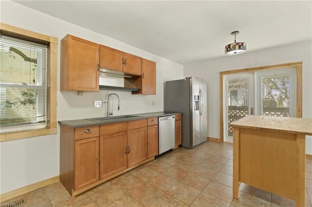 kitchen with a sink, stainless steel appliances, a healthy amount of sunlight, and brown cabinets