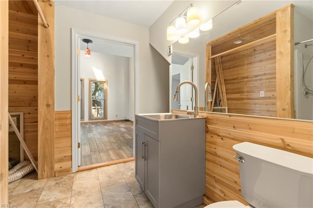 bathroom with a shower with curtain, vanity, wood walls, toilet, and a chandelier
