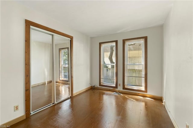 spare room featuring baseboards and wood finished floors