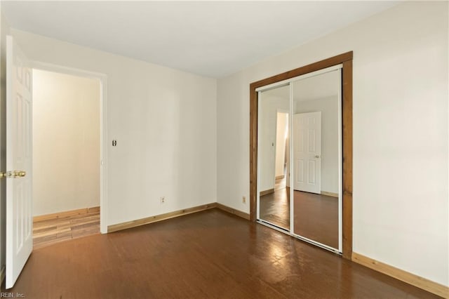 unfurnished bedroom with baseboards, wood finished floors, and a closet