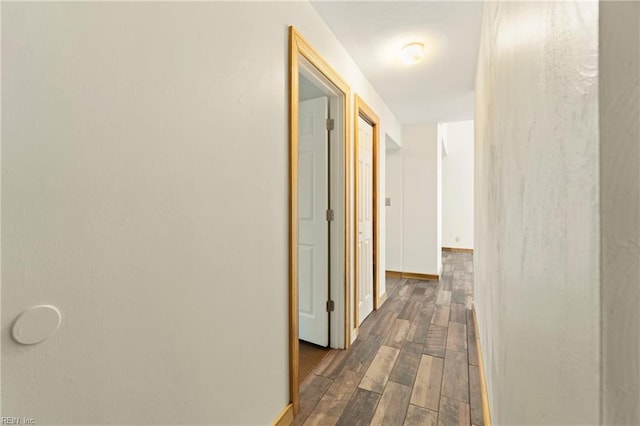 hall featuring dark wood-type flooring and baseboards