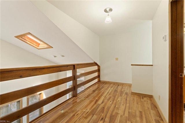 additional living space with lofted ceiling with skylight, baseboards, and wood finished floors