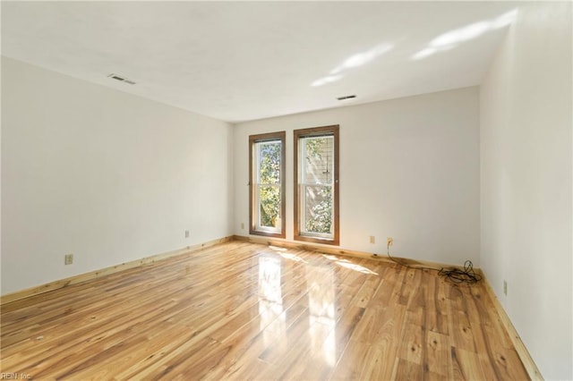 spare room featuring light wood-style flooring, baseboards, and visible vents