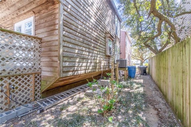 view of side of property featuring fence and central AC unit