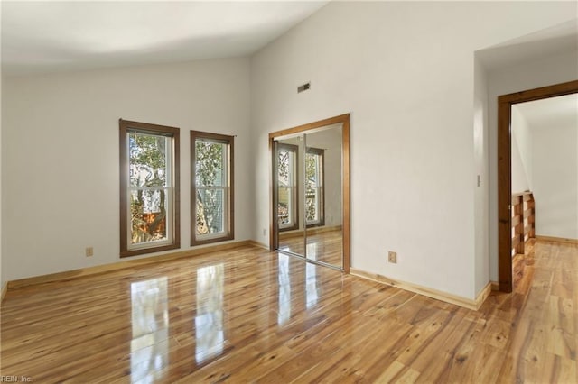 spare room with visible vents, high vaulted ceiling, baseboards, and light wood-type flooring